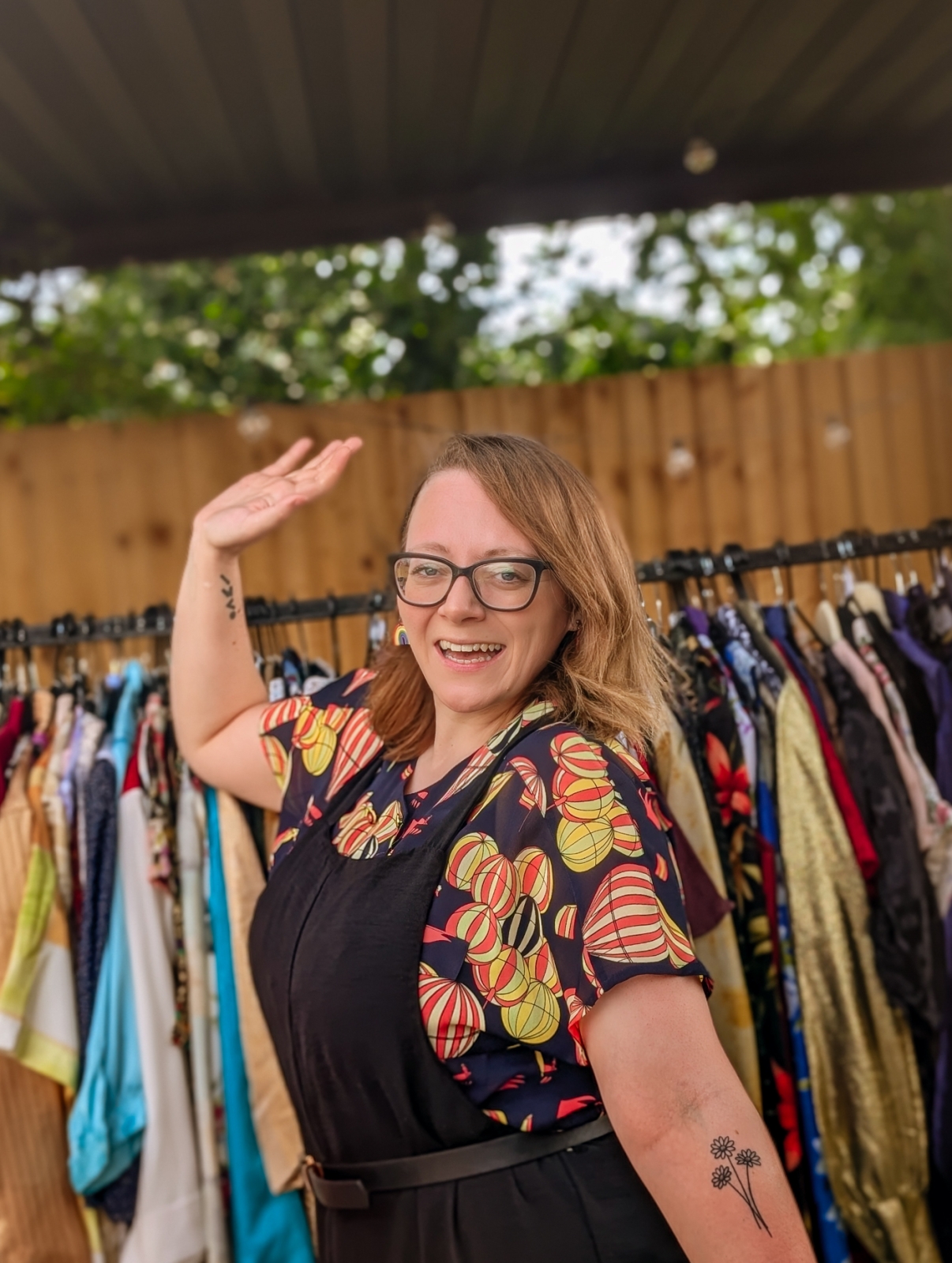 Adele standing in front of a rail of colourful vintage clothing